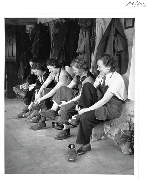 Women gardeners put on their clogs ready for work, World War II